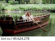 a boat trip for a guy and a girl along the canals and bays of the river overgrown with wild willows. Стоковое фото, агентство Ingram Publishing / Фотобанк Лори
