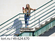 Young black female with coloured braids, looking at her smartphone with her feet resting on a skateboard.. Black female with coloured braids, looking at her smartphone with her feet resting on a skateboard. Стоковое фото, агентство Ingram Publishing / Фотобанк Лори