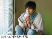Middle-aged woman smelling coffee from her cup near a window. Female in her 50s. Middle-aged woman smelling coffee from her cup near a window. Стоковое фото, агентство Ingram Publishing / Фотобанк Лори