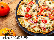 Pizza with sausage, tomato and capers on a pumpkin tortilla. Autumn pumpkin pizza. Стоковое фото, агентство Ingram Publishing / Фотобанк Лори
