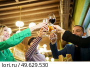 From below happy diverse male and female friend clinking glasses of alcohol during party in weekend in pub. Man and women proposing toast during party. Стоковое фото, агентство Ingram Publishing / Фотобанк Лори