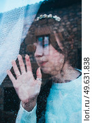 Sad woman alone in her home looking through a window in a rainy day. Стоковое фото, агентство Ingram Publishing / Фотобанк Лори