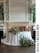 The presidium of the newlyweds in the banquet hall of the restaurant is decorated with candles and green plants, wisteria hangs from the ceiling. Стоковое фото, агентство Ingram Publishing / Фотобанк Лори