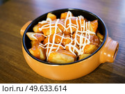 Delicious plate of patatas bravas, a typical Spanish dish, garnished with spicy sauce and served in a bowl on a wooden table in a restaurant.. Plate of patatas bravas, a typical Spanish dish, on restaurant table. Стоковое фото, агентство Ingram Publishing / Фотобанк Лори