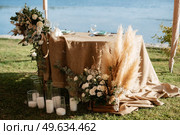 The presidium of the newlyweds in the banquet hall of the restaurant is decorated with candles and green plants, wisteria hangs from the ceiling. Стоковое фото, агентство Ingram Publishing / Фотобанк Лори