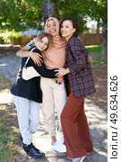 Positive young multiethnic female best friends in casual clothes smiling and looking at camera while cuddling in park on sunny day. Delighted young diverse ladies embracing and smiling in park. Стоковое фото, агентство Ingram Publishing / Фотобанк Лори