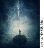Alone man stands on a small rock island, lost in the middle of the ocean under the stormy night sky. Failure and despair concept, seeking for help. Life crisis, surviving a hopeless situation. Стоковое фото, агентство Ingram Publishing / Фотобанк Лори