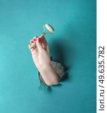 Women hand holding  jade massage roller at blue background. Front view. Beauty product for skin care. Стоковое фото, агентство Ingram Publishing / Фотобанк Лори