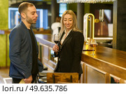 Cheerful multiracial man and woman with alcohol drinks smiling and looking at each other while having date in bar. Happy diverse couple spending time in pub. Стоковое фото, агентство Ingram Publishing / Фотобанк Лори