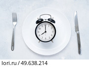 Intermitted farsting diet concept - empty plate with fork and knife and timer. Intermitted farsting diet concept. Стоковое фото, агентство Ingram Publishing / Фотобанк Лори