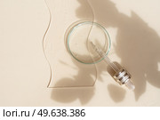 Glass petri dish with transparent pure serum for skin care on beige background, top view. Concept laboratory tests and research, natural organic cosmetic, natural cosmetics concept with leaves shadow. Glass petri dish with transparent pure serum for skin care. Стоковое фото, агентство Ingram Publishing / Фотобанк Лори