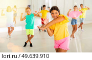 Smiling latin american preteen girl training vigorous dance with tweens. Стоковое фото, фотограф Яков Филимонов / Фотобанк Лори