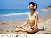 Black female in lotus pose doing mindfulness listening to a meditation with wireless headphones.. Black girl in lotus pose doing mindfulness listening to a meditation with wireless headphones. Стоковое фото, агентство Ingram Publishing / Фотобанк Лори