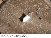 Gemstone pendulum. Magic healing Rock for Reiki Crystal Ritual, Witchcraft, spiritual esoteric practice. Healing crystals on brown background. Стоковое фото, агентство Ingram Publishing / Фотобанк Лори