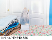 Ironing board with iron and folded apparel, household and homework concept. Ironing board with iron. Стоковое фото, агентство Ingram Publishing / Фотобанк Лори