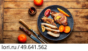 Pork on the bone baked in oranges, lime and tangerine. Meat in the plate on wooden table. Barbecue meat steak with citrus fruits. Стоковое фото, агентство Ingram Publishing / Фотобанк Лори