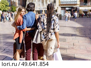 Blond lady with unrecognizable multiracial female friends walking on street pavement after shopping on sunny day. Diverse women walking on street with paper bags. Стоковое фото, агентство Ingram Publishing / Фотобанк Лори