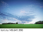 Rural landscape at dawn with green crops under a dramatic sunset sky. Стоковое фото, агентство Ingram Publishing / Фотобанк Лори