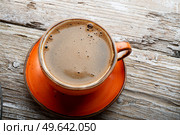 fresh boiled coffee served in beautiful prange cup around old style wooden background . close up. flat lay . Стоковое фото, агентство Ingram Publishing / Фотобанк Лори