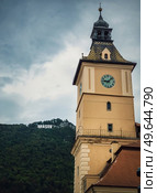 The council house clock tower with a beautiful view to the Brasov sign on top of the hill. Popular tourist location in Romania. Стоковое фото, агентство Ingram Publishing / Фотобанк Лори