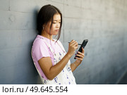Serious Chinese girl using her smartphone with a pen or stylus,outdoors Asian female wearing casual clothes.. Serious Chinese girl using her smartphone with a pen or stylus,outdoors. Стоковое фото, агентство Ingram Publishing / Фотобанк Лори