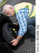 aged man changing leaking tire on the verge. Стоковое фото, агентство Ingram Publishing / Фотобанк Лори