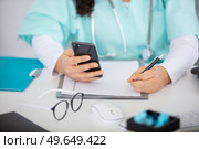 female doctor use a smartphone in her office. Стоковое фото, агентство Ingram Publishing / Фотобанк Лори