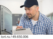 serviceman writing the appliance serial number on his paperwork. Стоковое фото, агентство Ingram Publishing / Фотобанк Лори
