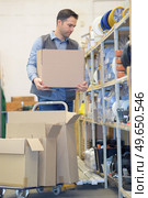 male worker with cardboard boxes by storage racking. Стоковое фото, агентство Ingram Publishing / Фотобанк Лори