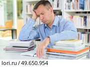 Tired man with stack of books. Стоковое фото, агентство Ingram Publishing / Фотобанк Лори