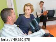 mid-adult man with crutches and girlfriend waiting in hospital. Стоковое фото, агентство Ingram Publishing / Фотобанк Лори