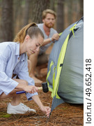 young couple helping each other to pitch tent. Стоковое фото, агентство Ingram Publishing / Фотобанк Лори