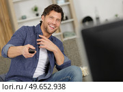 amused man watching tv at home. Стоковое фото, агентство Ingram Publishing / Фотобанк Лори