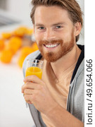 young man drinking orange juice at home. Стоковое фото, агентство Ingram Publishing / Фотобанк Лори