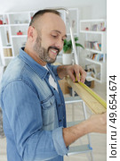 man measuring wood piece for furniture assembling. Стоковое фото, агентство Ingram Publishing / Фотобанк Лори