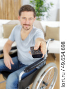 handicap man using remote control while watching television. Стоковое фото, агентство Ingram Publishing / Фотобанк Лори