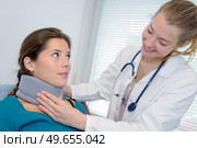 smiling female doctor adjusting neck brace on pretty patient. Стоковое фото, агентство Ingram Publishing / Фотобанк Лори