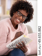 woman doing crosswords in living room. Стоковое фото, агентство Ingram Publishing / Фотобанк Лори