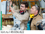 young worker pressing controls for workshop machinery. Стоковое фото, агентство Ingram Publishing / Фотобанк Лори