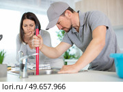 worried housewife watching plumber plunger her sink. Стоковое фото, агентство Ingram Publishing / Фотобанк Лори