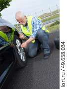 retired man has to change punctured wheel. Стоковое фото, агентство Ingram Publishing / Фотобанк Лори