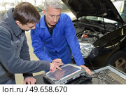 auto mechanic teacher and trainee performing tests at mechanic school. Стоковое фото, агентство Ingram Publishing / Фотобанк Лори