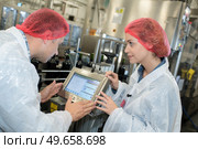 Factory workers in discussion over production line monitor. Стоковое фото, агентство Ingram Publishing / Фотобанк Лори