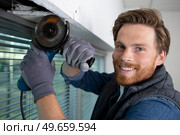 young male builder uses an angle grinder. Стоковое фото, агентство Ingram Publishing / Фотобанк Лори