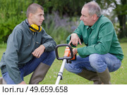 young gardener being shown how to operate a strimmer. Стоковое фото, агентство Ingram Publishing / Фотобанк Лори