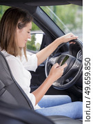 woman looking down at her smartphone while driving a car. Стоковое фото, агентство Ingram Publishing / Фотобанк Лори