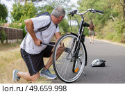 cyclist inflating bike tyre in forest. Стоковое фото, агентство Ingram Publishing / Фотобанк Лори