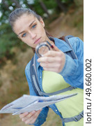 female hiker shielding her eyes while holding compass in forest. Стоковое фото, агентство Ingram Publishing / Фотобанк Лори