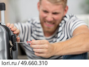 frustrated man trying to open locked suitcase with screwdriver. Стоковое фото, агентство Ingram Publishing / Фотобанк Лори