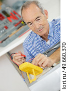 a senior serviceman using multimeter. Стоковое фото, агентство Ingram Publishing / Фотобанк Лори